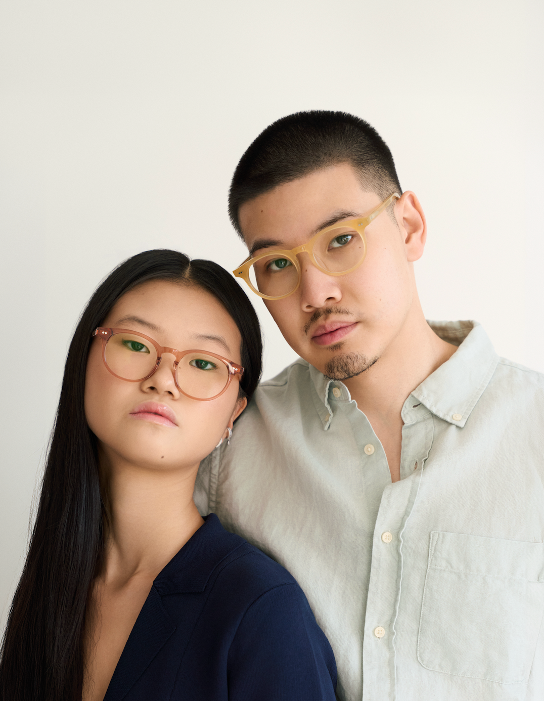 Two people wear KayTran Eyewears Bailey - Sienna glasses, standing close together against a plain background.