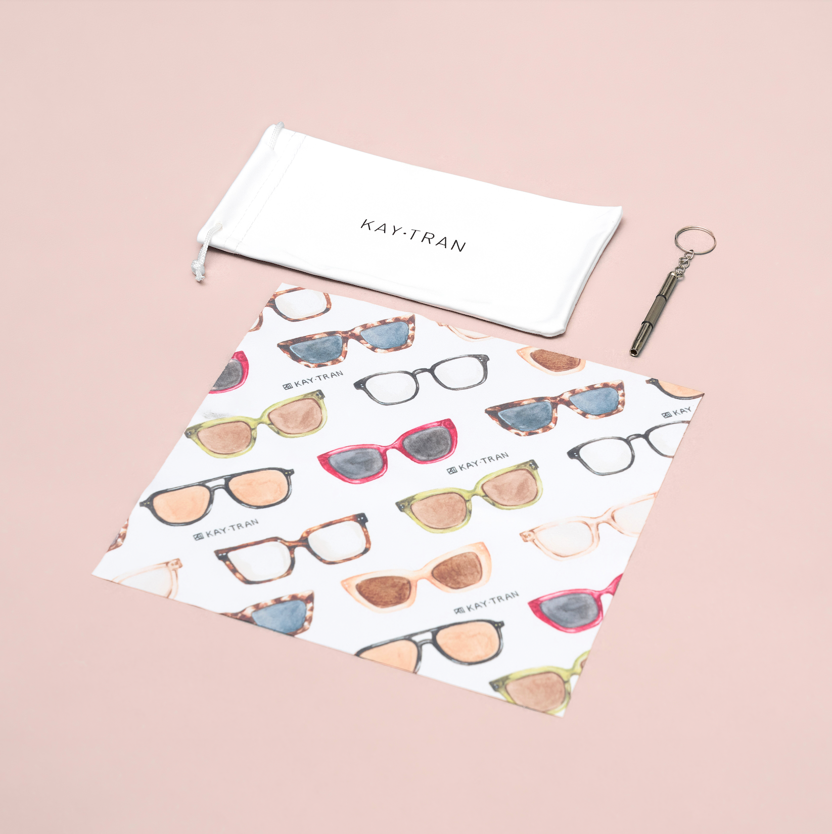 KayTran Eyewears KayTran x Ton Ton Art Tune Up Kit with pouch, illustrated cloth, and keychain tool on pink background.